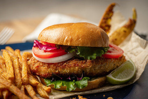 A fish burger is a type of sandwich that consists of a breaded and fried or grilled fish patty served on a bun with various toppings and condiments. The fish patty is typically made with white fish such as cod, haddock, or pollock, and it may be seasoned with spices or herbs for added flavor.\n\nThe bun is usually a soft, sesame seed bun that is lightly toasted to provide a bit of crunch. Toppings for the fish burger may include lettuce, tomato, onion, pickles, and cheese, among others. Common condiments include tartar sauce, mayonnaise, ketchup, and mustard.\n\nThe texture of a fish burger is typically moist and flaky, with a crispy exterior from the breading or grilling. The flavors are often savory and slightly salty, with a hint of seafood taste that pairs well with the other ingredients in the burger.\n\nFish burgers are often seen as a healthier alternative to traditional beef burgers, as they are lower in fat and calories while still providing a satisfying and flavorful meal option. They are commonly found on menus at fast-food restaurants and seafood establishments, and can be enjoyed as a quick snack or a full meal.