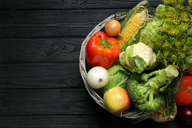 istock Different fresh vegetables in wicker basket on black wooden table, top view with space for text. Farmer harvesting 1488971469