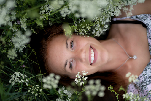 Beautiful young woman lying among white wild flowers