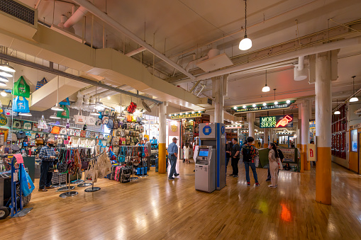 Tourists shop the interior marketplace of shops and food establishments inside the Pike Place Market in the waterfront harbor and downtown district of Seattle, Washington.