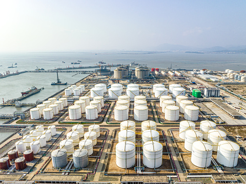 Many neatly arranged large cylindrical storage tanks by the seaside