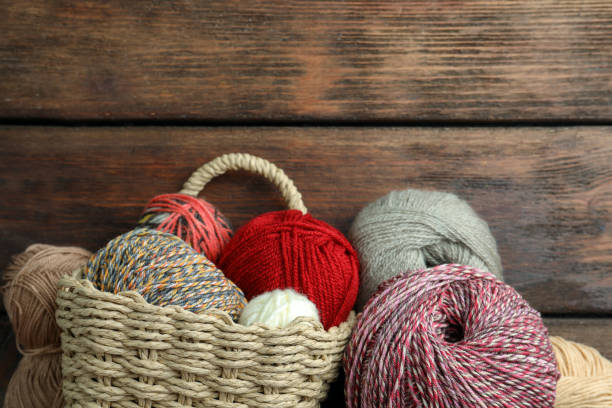 istock Soft woolen yarns on wooden table, flat lay. Space for text 1488978111