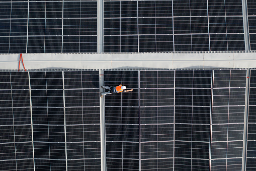Aerial view of maintenance manager fixing solar panels on a roof.
