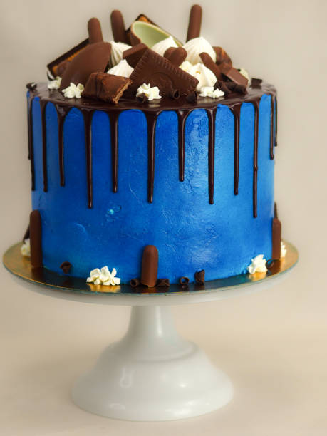 istock blue frosted icing cake with dark chocolate icing and mixed sweets as topping isolated on white background 1488991165