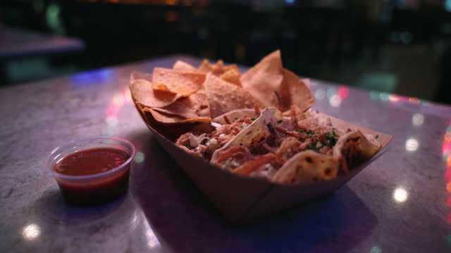 Close-Up Shot of Delicious Fish Street Tacos and Corn Tortilla Chips from Local Business Taco Shop in San Diego under Vibrant-Colored Christmas Lights