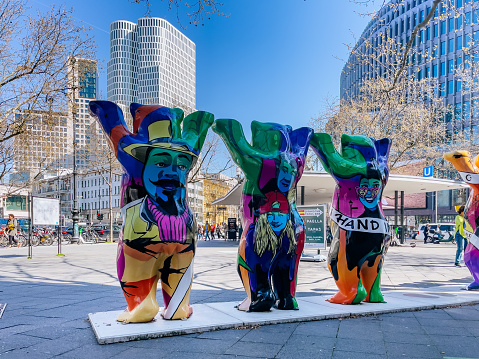 This photo captures the colorful and vibrant spirit of Berlin's Mitte District on a sunny spring day. In the center of the frame, a row of colorful bears, Berlin's symbols, stand with raised paws on Kurfürstendamm, one of the city's most bustling streets. The photo showcases the lively atmosphere of the city and is a perfect image for showcasing the excitement and energy of Berlin.