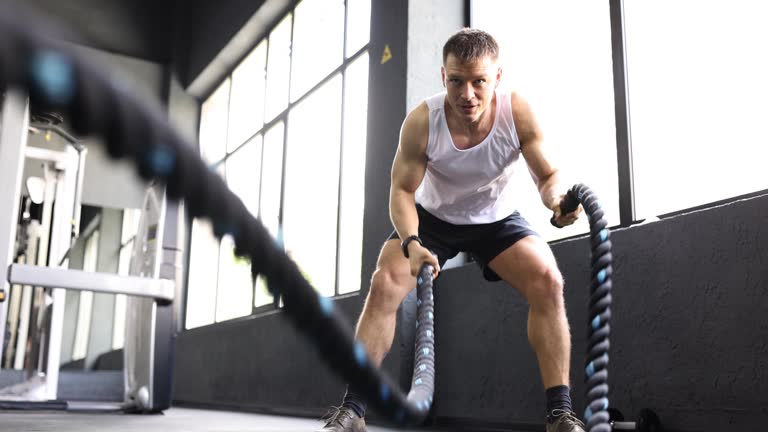 Man athlete waving ropes in gym 4k movie slow motion