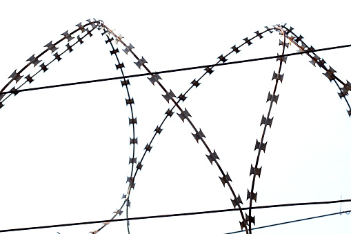 Barbed wire set against a deep blue sky
