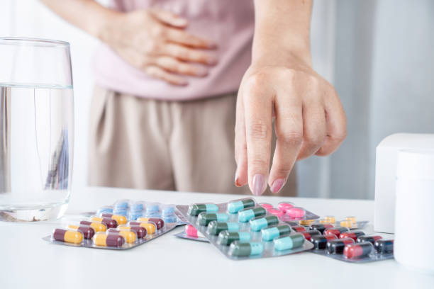 腹痛とダリア感染症の治療:抗生物質の錠剤を服用している女性の手の接写 - single flower plant flower close up ストックフォトと画像