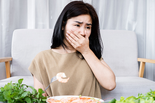 Asian Woman Experiencing Nausea and Vomiting Due to Shrimp Allergy
