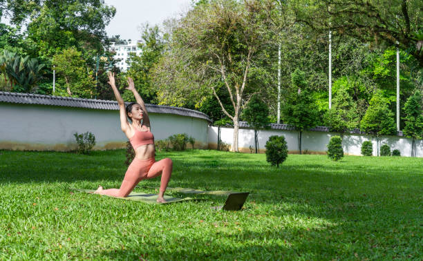 istock Asian Woman doing yoga with an on-line tutorial at outdoor park 1489024224