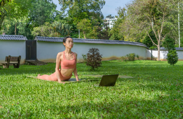 istock Asian Woman doing yoga with an on-line tutorial at outdoor park 1489024225