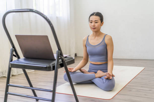 istock Asian Woman doing yoga with an on-line tutorial at indoor 1489024772