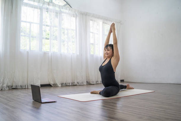 istock Asian Woman doing yoga with an on-line tutorial at indoor 1489027950