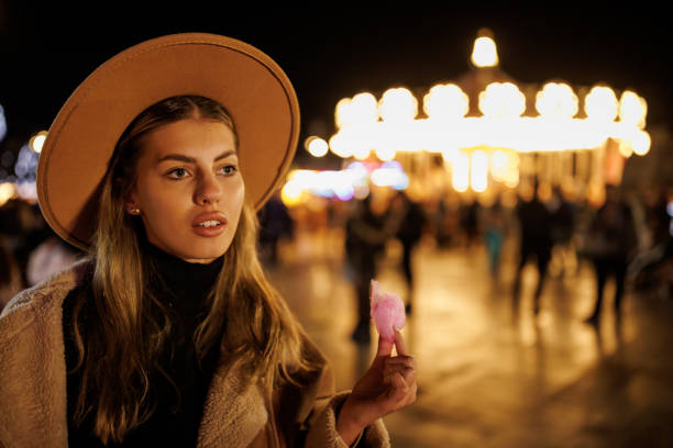 Young Woman Eating Cotton Candy In Amusement Park