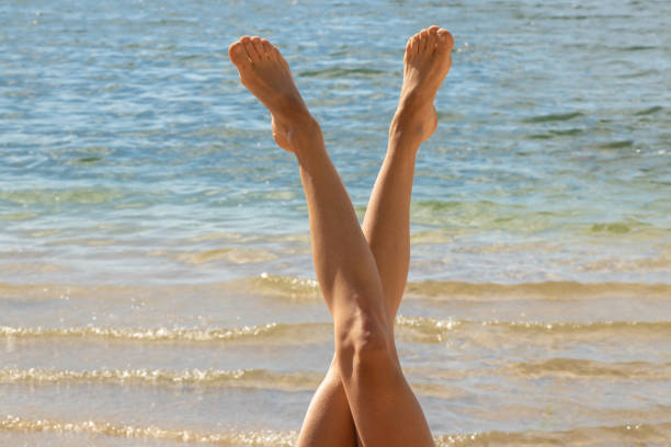 tanned legs of a young girl on a background of water in the shape of a letter v in summer tanned legs of a young girl on a background of water in the shape of a letter v woman legs open stock pictures, royalty-free photos & images