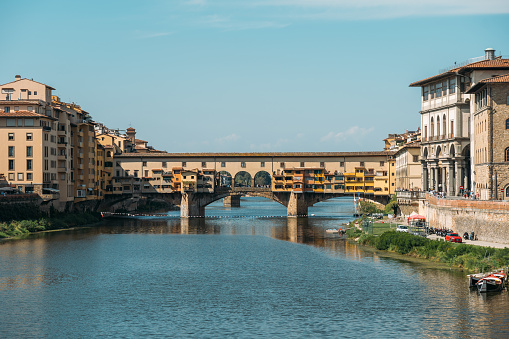 Stunning panoramic view of the bridge Ponte de Vecchio old bridge over the Arno River in Florence, Italy on sunny summer cloudless day. Concept of ancient sights of stone architecture. Copyspace.