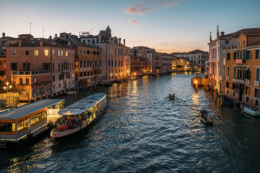 Evening top view of the Grand Canal in Venice with glowing lights on the blue sky. The concept of tourist trips in the ancient European city in Italy. Copyspace.