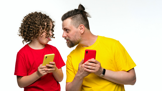 Concerned dad checks daughter Internet activity. Man in basic t-shirt holds mobile and looks at cell phone female child. Girl mischievous and shows tongue. Parental control. Rules behave with phone