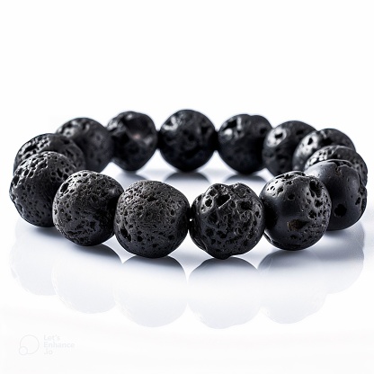 A beaded bracelet made with dark volcanic rocks, against a white background