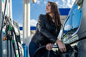 Happy woman refueling the gas tank at fuel pump.