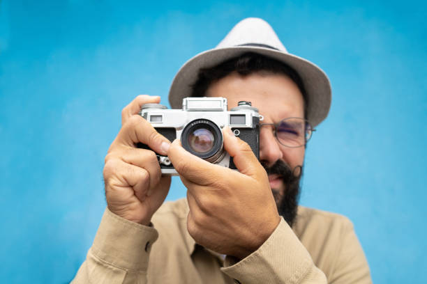 istock A young hipster man with hat is making a photo with a retro camera 1489040316