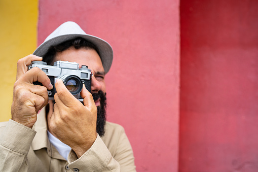 A hipster man is maknig a photo using a vintage camera