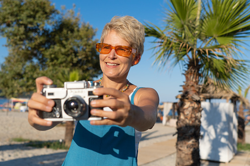 A middle-aged woman using a vintage camera on a vacation