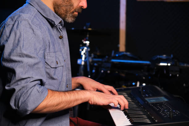 istock Musician man playing keyboard synthesizer piano in a recording studio. 1489042334