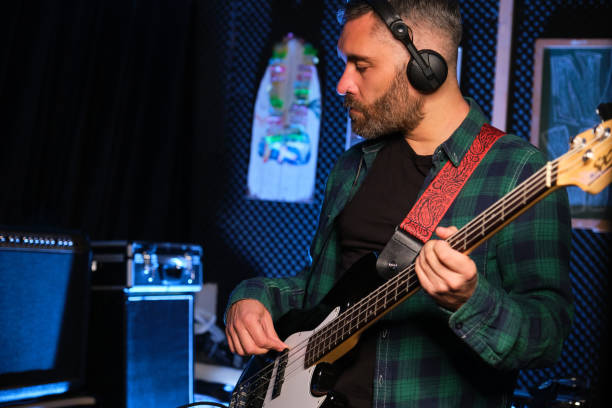 istock Musician practicing electric bass playing with headphones at recording studio. 1489042377