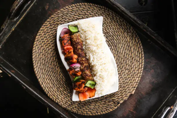 Chelo kabab or chello kebab with chicken tikka and rice served in dish isolated on red mat top view on table arabic food