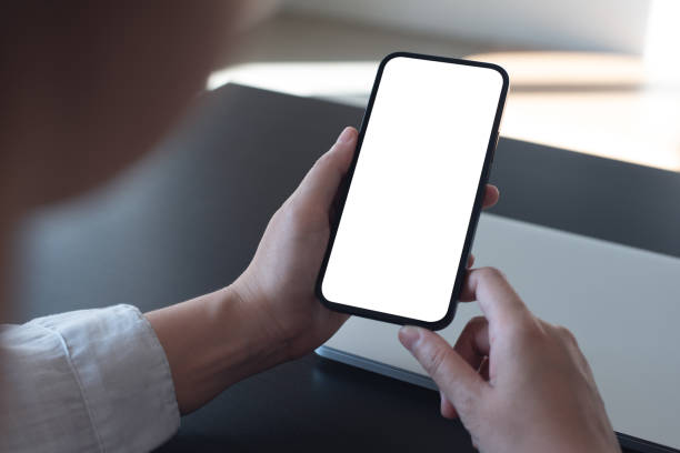 istock Mockup, blank screen cell phone. women hand holding, using mobile phone, working on laptop computer at  office. white empty space for advertisement. contact business, web template or mobile app design 1489047599