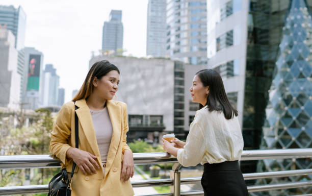 istock Two Asian Women Talking About Life at Work on Overpass During Coffee Break. 1489049877