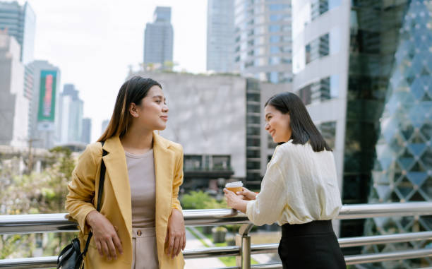 istock Two Asian Women Talking About Life at Work on Overpass During Coffee Break. 1489049878