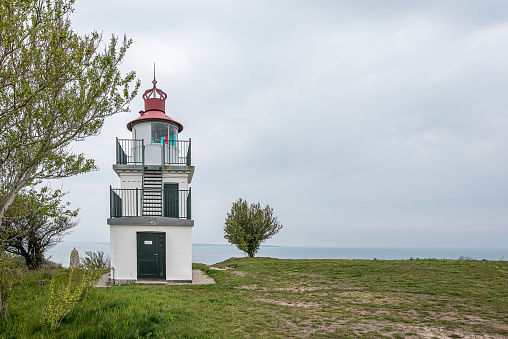 Spodsbjerg lighthouse overlooking a green beach meadow and the sea in the distance, Hundested, Denmark, May 10, 2021
