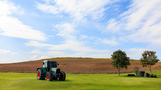 green tractor is parked in the middle of the farmland and blue sky background
