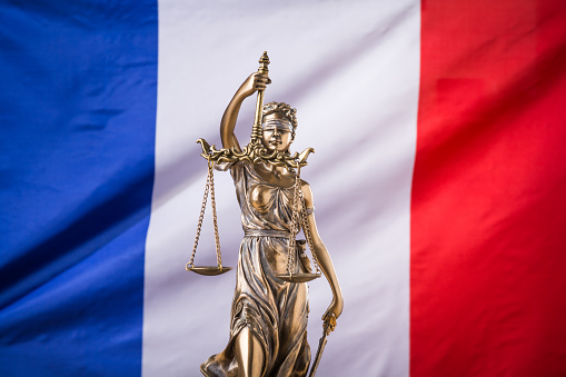 The statue of justice Themis or Justitia, the blindfolded goddess of justice against the flag of France, as a legal concept