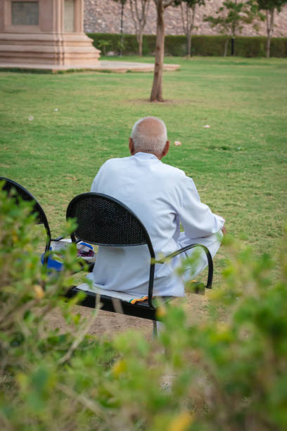 istock old man isolated sitting alone at iron chair at park from back at evening 1489052018