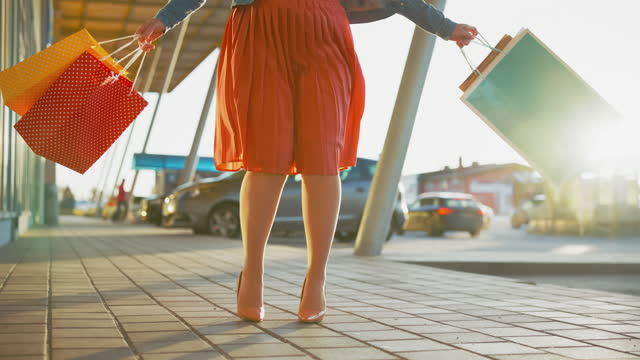 SLO MO Ecstatic woman in a skirt dancing with shopping bags in front of a store