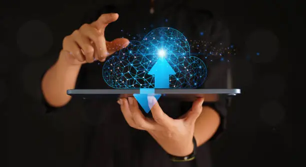 Photo of Cloud Computing with man using tablet on black background and blue glowing link lines.
