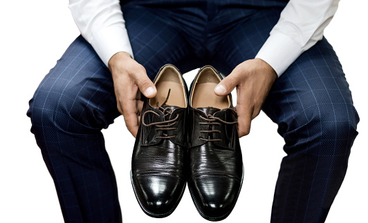 Elegant man holding stylish men's shoes  isolated on white background