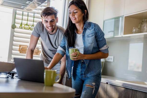 istock Young happy couple using laptop in the kitchen. 1489056362