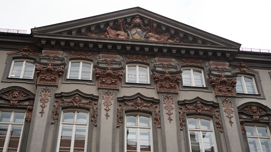 A historic building with intricate architectural detailing on the roof, featuring numerous windows, Munich