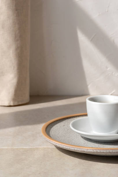 istock Minimalist composition with coffee cup, plate on beige stone table, with aesthetic sunlight shadow on neutral wall with linen curtain, morning coffee concept, copy space 1489058326