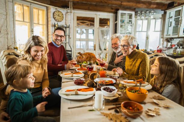 istock Happy multi-generation family communicating while having Thanksgiving lunch in dining room. 1489059462