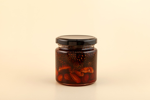 Jam with pine cones, almond nuts and walnuts in glass jar. Healthy syrup to support immune system.