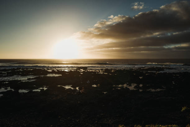 Punta del Hidalgo, Spain, April 5, 2023: People by the sea at sunset on April 5, 2023 in Punta del Hidalgo, Tenerife, Canary Islands, Spain. People enjoy a warm spring sunset in Punta del Hidalgo coastline.