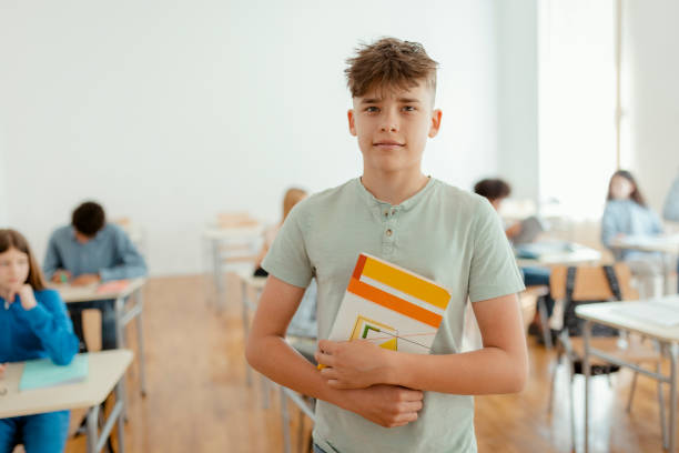 Portrait of confident elementary schoolboy in classroom, looking at camera