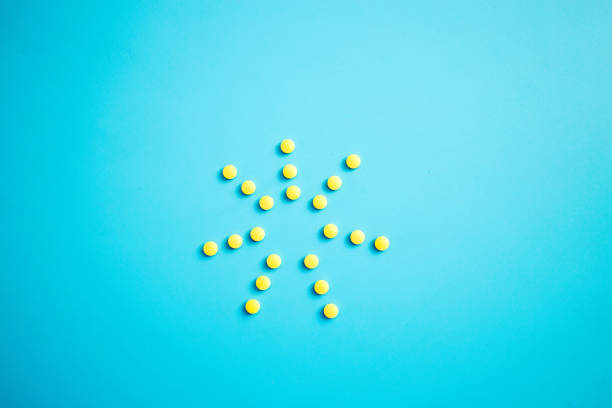 istock A sun of yellow pills from a bottle on a blue background. 1489062875