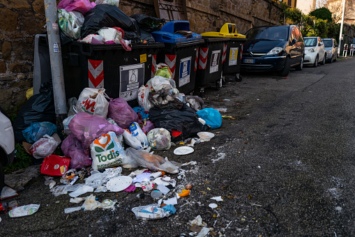 Rome, Italy, January 4, 2023: Dirt and trash in the streets on January 4, 2023 in Rome, Italy. Dirt, trash and waste cumulated by a trash can in a central road of Rome.
